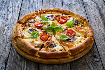 Circle pizza with boiled ham and  mushrooms on wooden table
