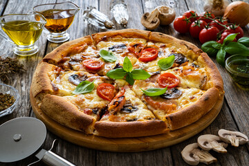 Circle pizza with boiled ham and  mushrooms on wooden table
