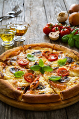 Circle pizza with boiled ham and  mushrooms on wooden table
