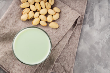 Obraz na płótnie Canvas Pistachio milk in a glass on a gray concrete background. Organic lactose free pistachio milk and pistachios. Top view. Copy space