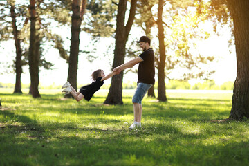Fathers day. Happy young dad having fun and spins little daughter outdoors. Single daddy with child...