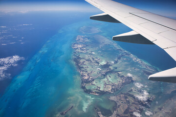 Naklejka na ściany i meble Aerial view from the plane flying across the Caribbean looking down on the Caribbean Sea and the beautiful islands of the tropics in the Bahamas