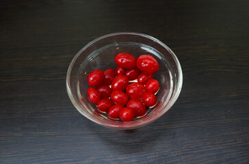 Many Red cherries in a Glass bowl on black wooden background.