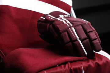 Dark red ice hockey gear glove on dark jersey close up of ice hockey equipment