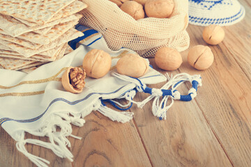 Passover celebration concept. Matzah, red kosher and walnut. Traditional ritual Jewish bread matzah, kippah and tallit on old wooden background. Passover food. Pesach Jewish holiday. Toned image.