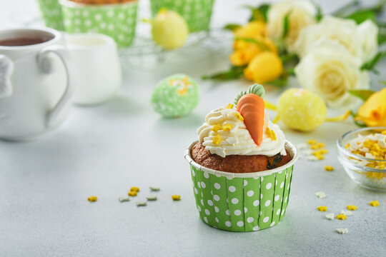 Carrot cake cupcakes for Easter. Carrot cupcakes with cream cheese frosting decorated with tiny marzipan carrots on white background. Happy Easter and spring holiday concept. Holydays homemade dessert