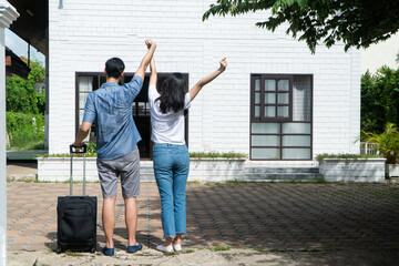 Happy couple in front of the New Home On Moving In Day, and start a new life family. Concept of homeowner and relocation