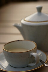 Close up of tea pot and tea cup. The photo is focused on the tea cup in the foreground. This photo...