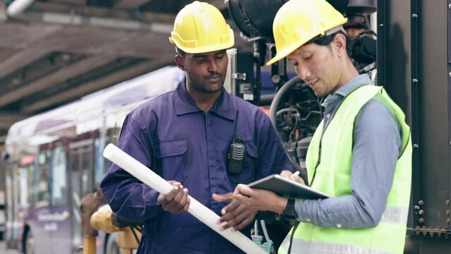 Structural engineers and construction workers are holding blueprints inspecting structure. sky train track construction in city. Blue collar wears a safety hardhat while working on construction site.	