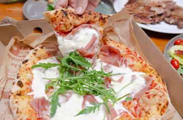 A baker making bread in the kitchenPizza with parma ham Italian style in a paper box