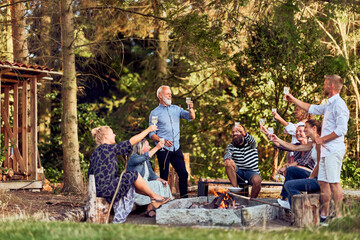Friends toasting with wine around a campfire