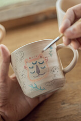 Close up shot of a woman potter painting a cup