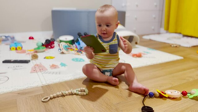 Baby kid is play with the phone on the floor. funny baby with a pacifier explores the phone sits on the floor play shakes his hand. happy family kid dream concept. baby play with lifestyle smartphone