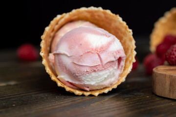 Waffle cone with white pink cream ice cream and raspberries