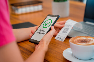 Woman using contactless payment by mobile phone with QR code at cafe