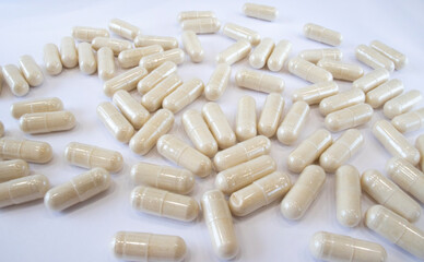 Fototapeta na wymiar Beige capsules on a white background. Medicines or heart health supplements.