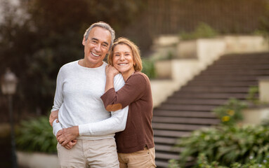 Happy Senior Couple Embracing Smiling To Camera Standing In Park