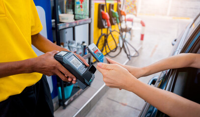 Woman using contactless payment by mobile phone with QR code at car filling station