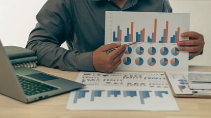 Business finance manager holding financial graph document to analyze company monthly expenses while...