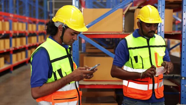 Two Indian employees use their mobile phones to drink water during the break from work. Warehouse worker resting. Inventory and wholesale concept