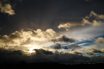 Obraz na płótnie Canvas Dramatic sunrise through black clouds