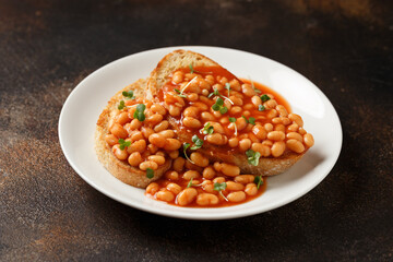 Baked beans on toast in tomato sauce on white plate