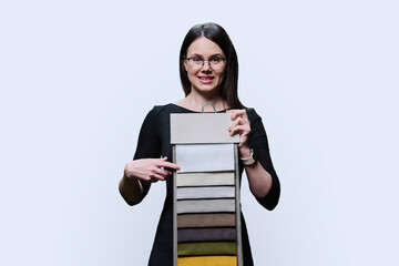 Young woman choosing decorative fabrics for interior, on white background