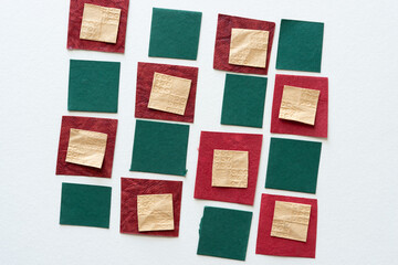 red, green, and yellow textured paper tiles arranged in a grid form on white