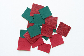 small pile of green and red textured paper tiles on white
