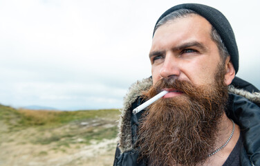 photo of man smoking cigarette in the mountain, copy space. man smoking cigarette outdoor.