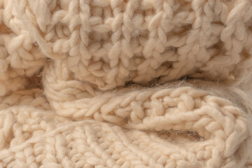 A fragment of beige knitted fabric, knitted from white sheep wool.