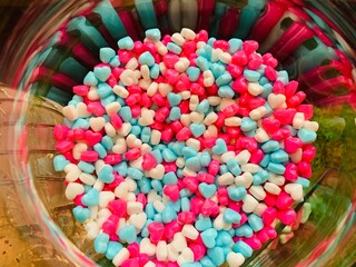 Heart shaped mints in blue, white and pink colors in a glass bowl