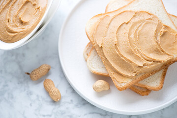 White plate with peanut butter sandwiches on a light-grey marble background, middle close-up, horizontal shot, elevated view