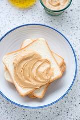 Sandwiches with peanut butter in a white plate, vertical shot on a light-grey granite background
