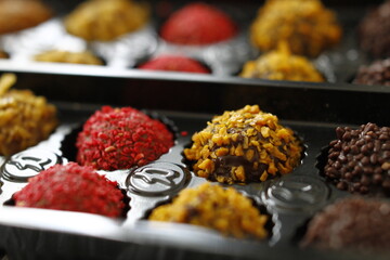 Close up macro photo of brightly colored chocolate truffles from just opened box with red and yellow sprinkles 