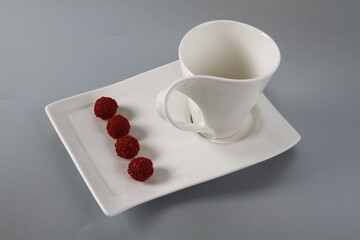 Obraz na płótnie Canvas Tasty chocolate candy truffles on white dish next to a coffee mug