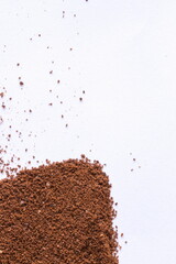 A pile of scattered ground coffee on a white background. The gra