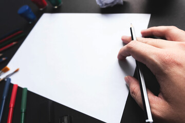 Man hand start using pencil drawing on empty white sheet of paper with art tools