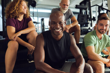 Smiling friends sitting on steps in a gym