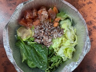 Takeaway bowl of brown rice with salmon and vegetables in an eco-friendly restaurant container. Raw salmon with rice and vegetables. Types of bowls of healthy and useful food