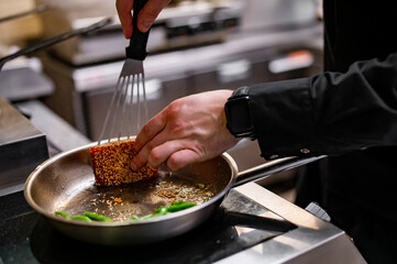 man chef cooking fried tuna fish and green bean in frying pan on kitchen