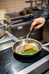 man chef cooking fried tuna fish and green bean in frying pan on kitchen