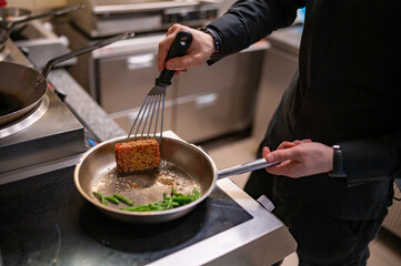 man chef cooking fried tuna fish and green bean in frying pan on kitchen