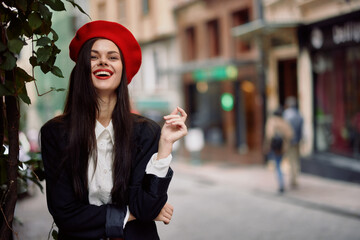 Fototapeta premium Girl smile with teeth stands on the street in the city in a jacket and red beret, cinematic french fashion style clothing, travel to istanbul