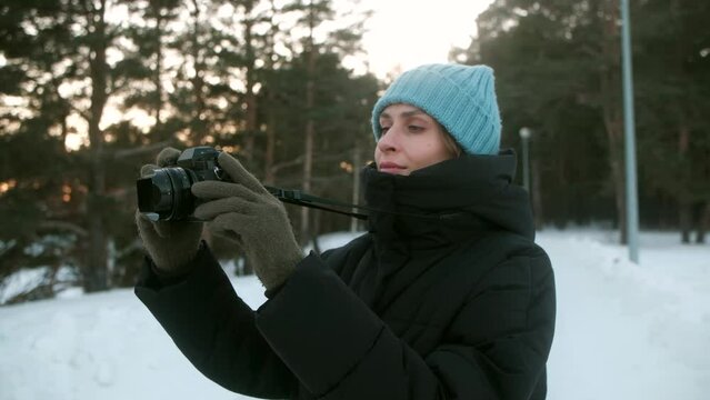 A young woman photographer takes pictures in a winter forest on camera. photo tourism. High quality 4k footage