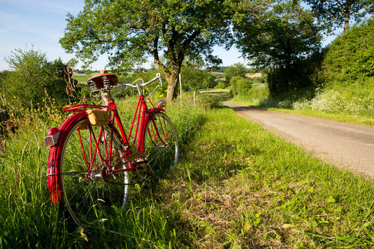 Vieux vélo rouge sur un chemin de campagne.