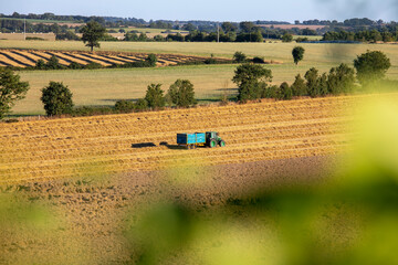 Agriculteur au volant de sa machine dans les champs pendant les moisson, paysage de France.