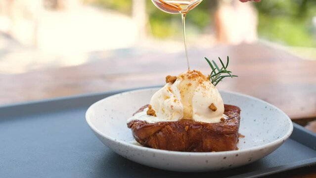 Honey is pouring on the vanilla ice cream on the toast.