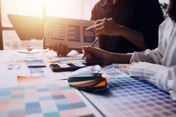 Close up ux developer and ui designer brainstorming about mobile app interface wireframe design on table with customer breif and color code at modern office.Creative digital development agency