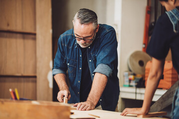 Professional senior cauasian man working woodworking handmade with tools in wood workshop, Timber factory industry.